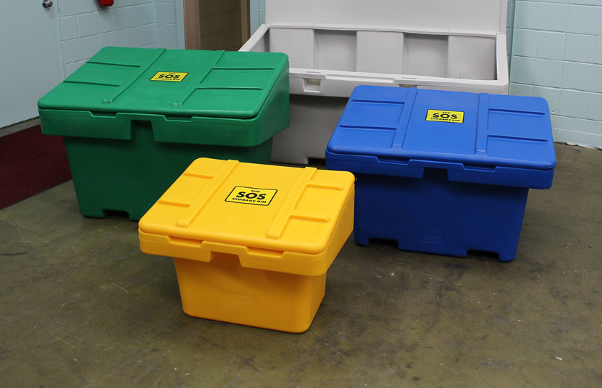 Three colorful salt storage bins (green, yellow, and blue) arranged indoors.